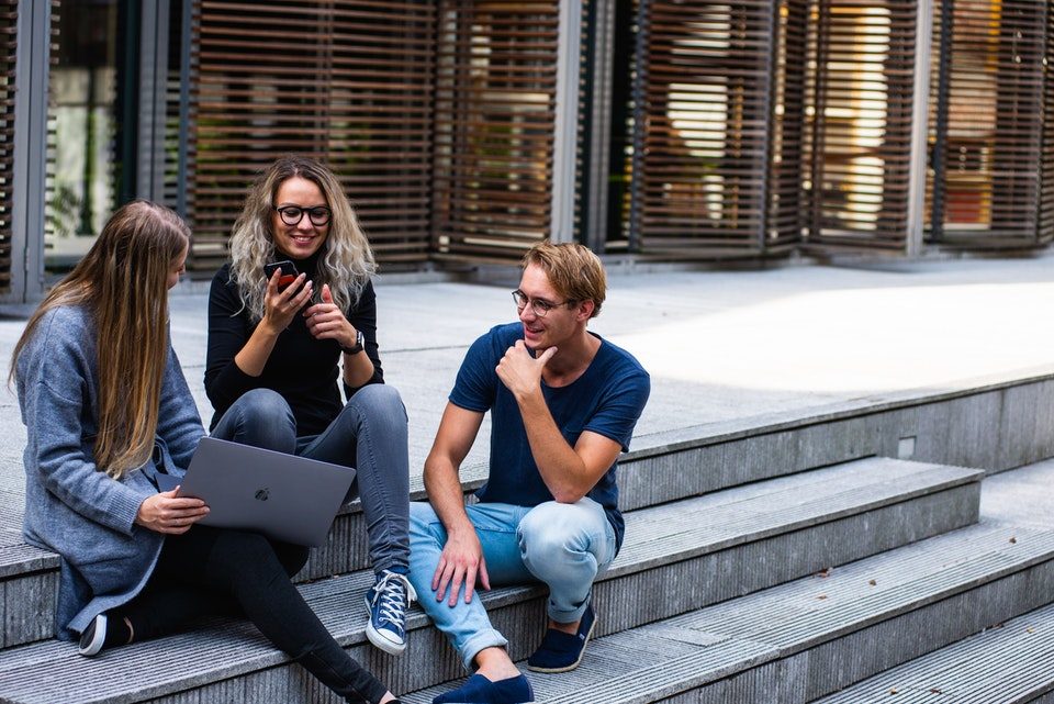 three persons sitting on the stairs talking to each other